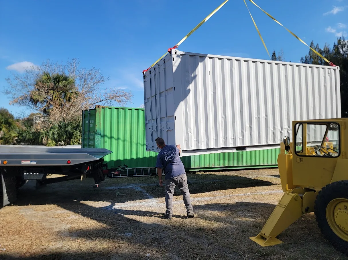 White shipping container being lifted in the company yard.