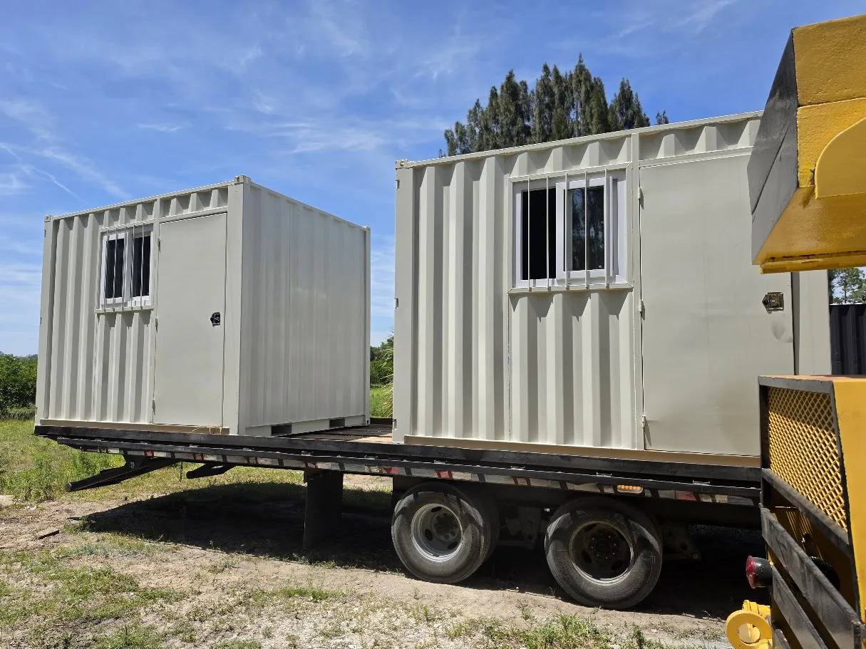 Two white compact container offices with windows on a delivery trailer.