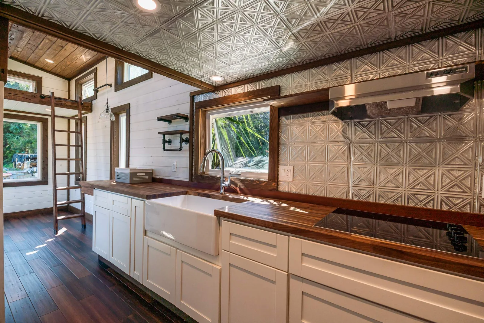 Finished tiny house kitchen with white cabinets and wood ceiling.